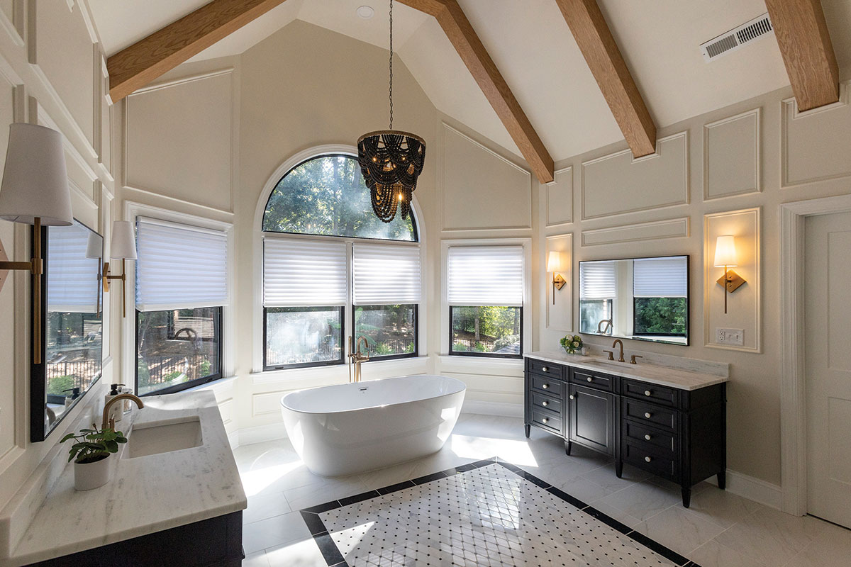 The master bathroom makes a luxe statement, with wooden beams, a beaded chandelier, custom molding, and a designed tile “rug.”